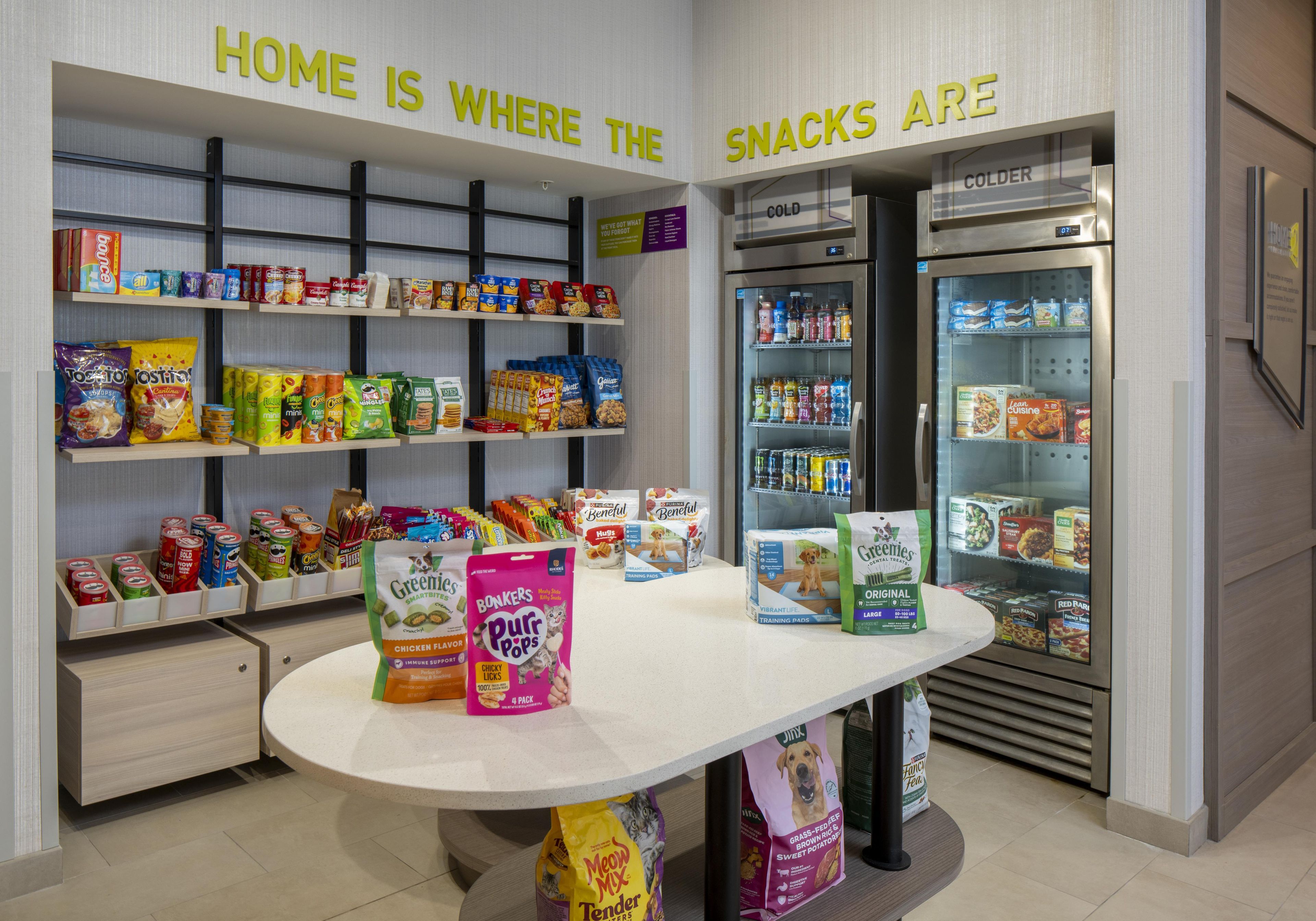 A snack and pet food display area with various products and a refrigerator.