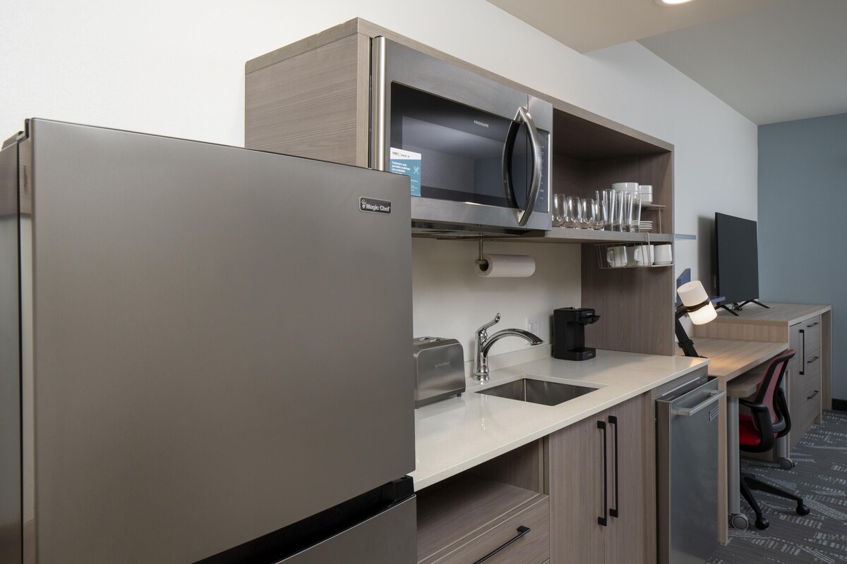 Una kitchenette equipada con refrigerador, microondas, tostadora, pileta y alacenas.