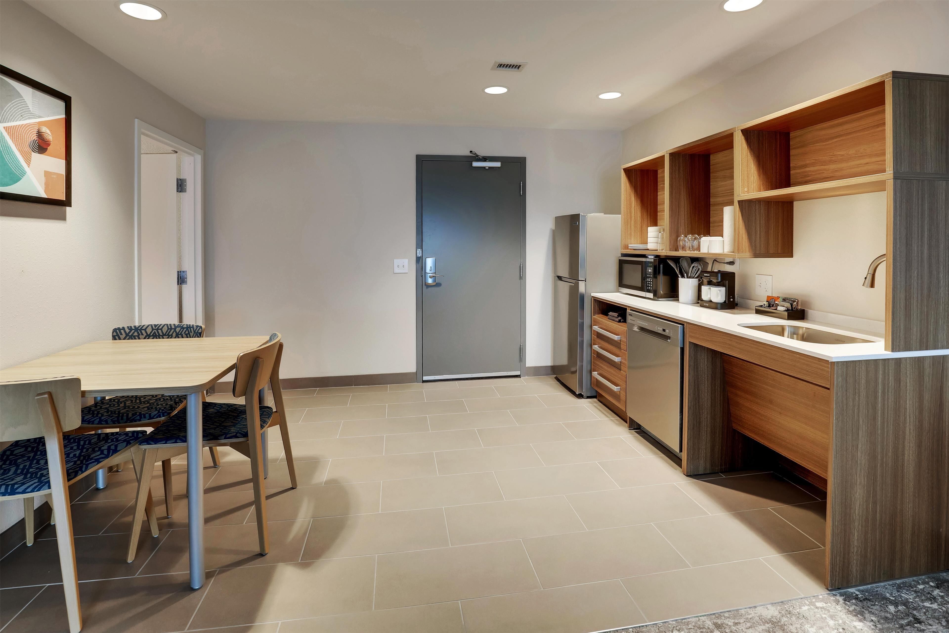 A modern kitchen with a wooden countertop, built-in appliances, and a dining area with a table and chairs.