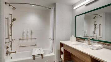 A modern bathroom with a walk-in shower, a vanity with a mirror, and a small stool.