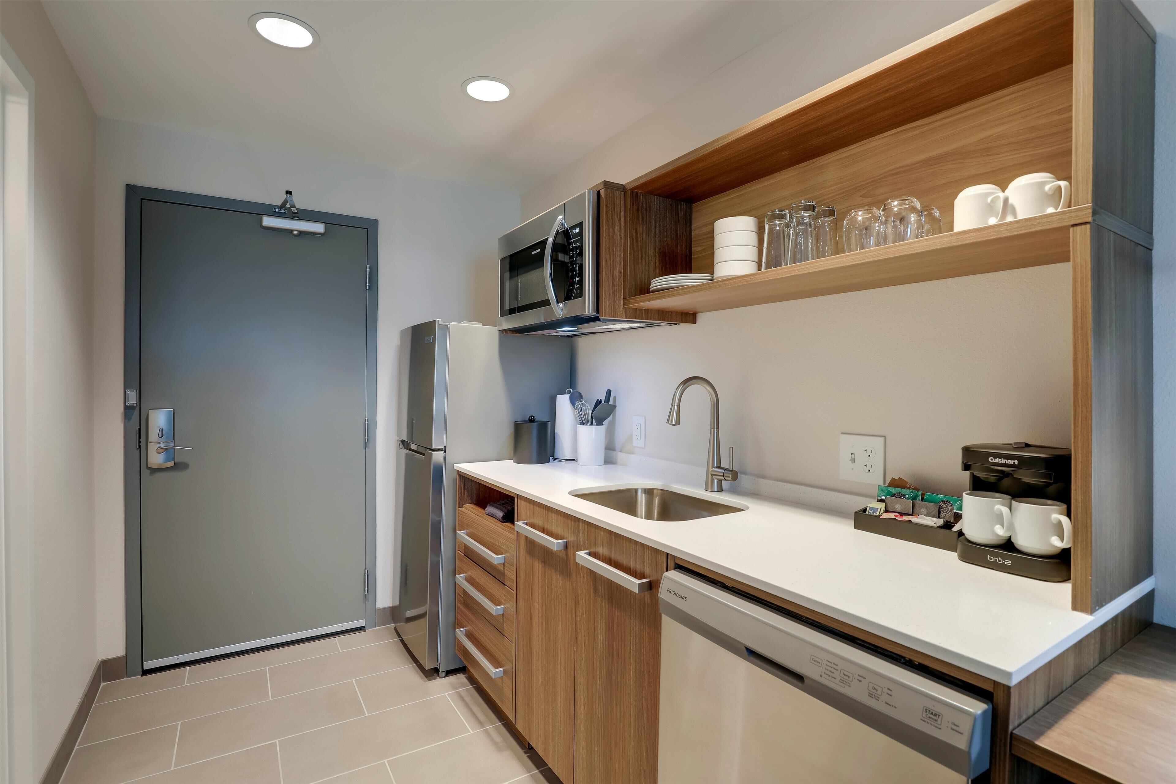 A modern kitchen with a built-in microwave, stainless steel refrigerator, and a dishwasher.