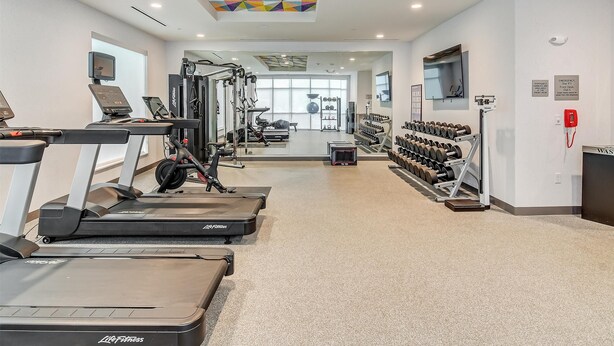 A gym with treadmills, weight machines, and dumbbells. - Home2 Suites By Hilton Crestview I-10 (Crestview)