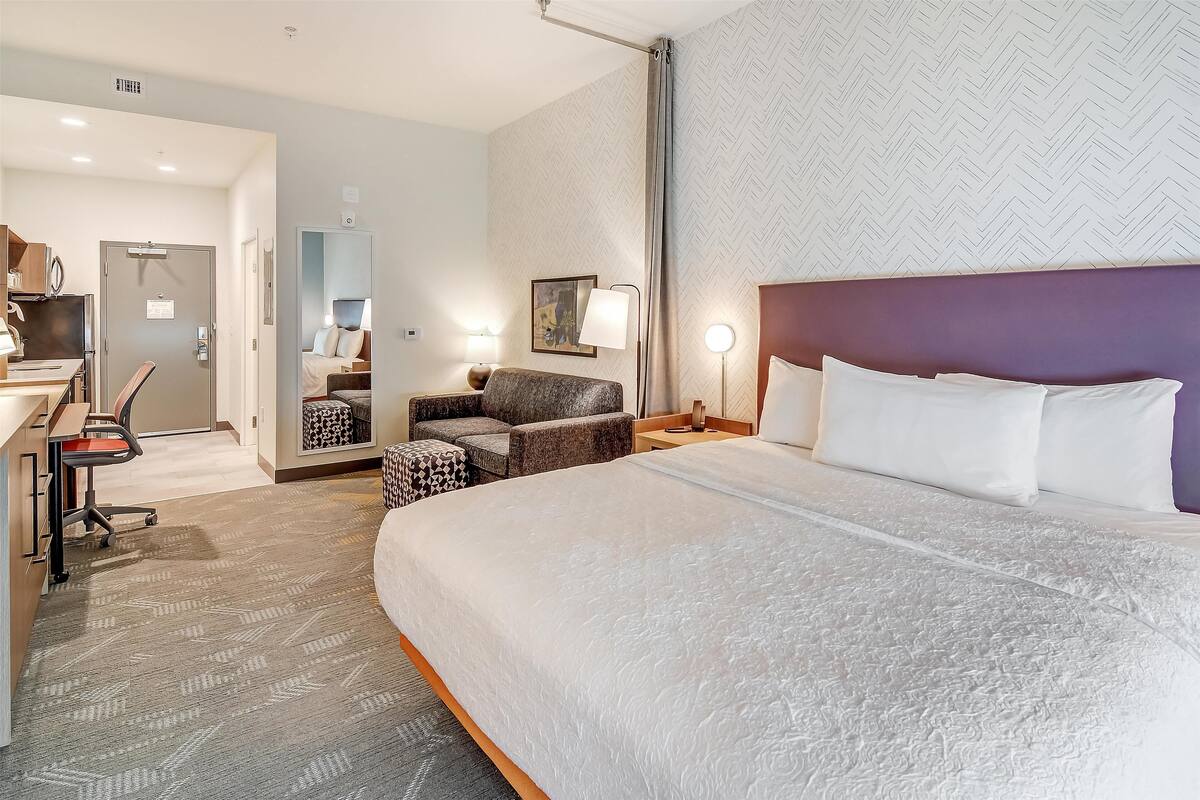 Une chambre d’hôtel avec un grand lit, un bureau avec une chaise, un canapé et une petite table.