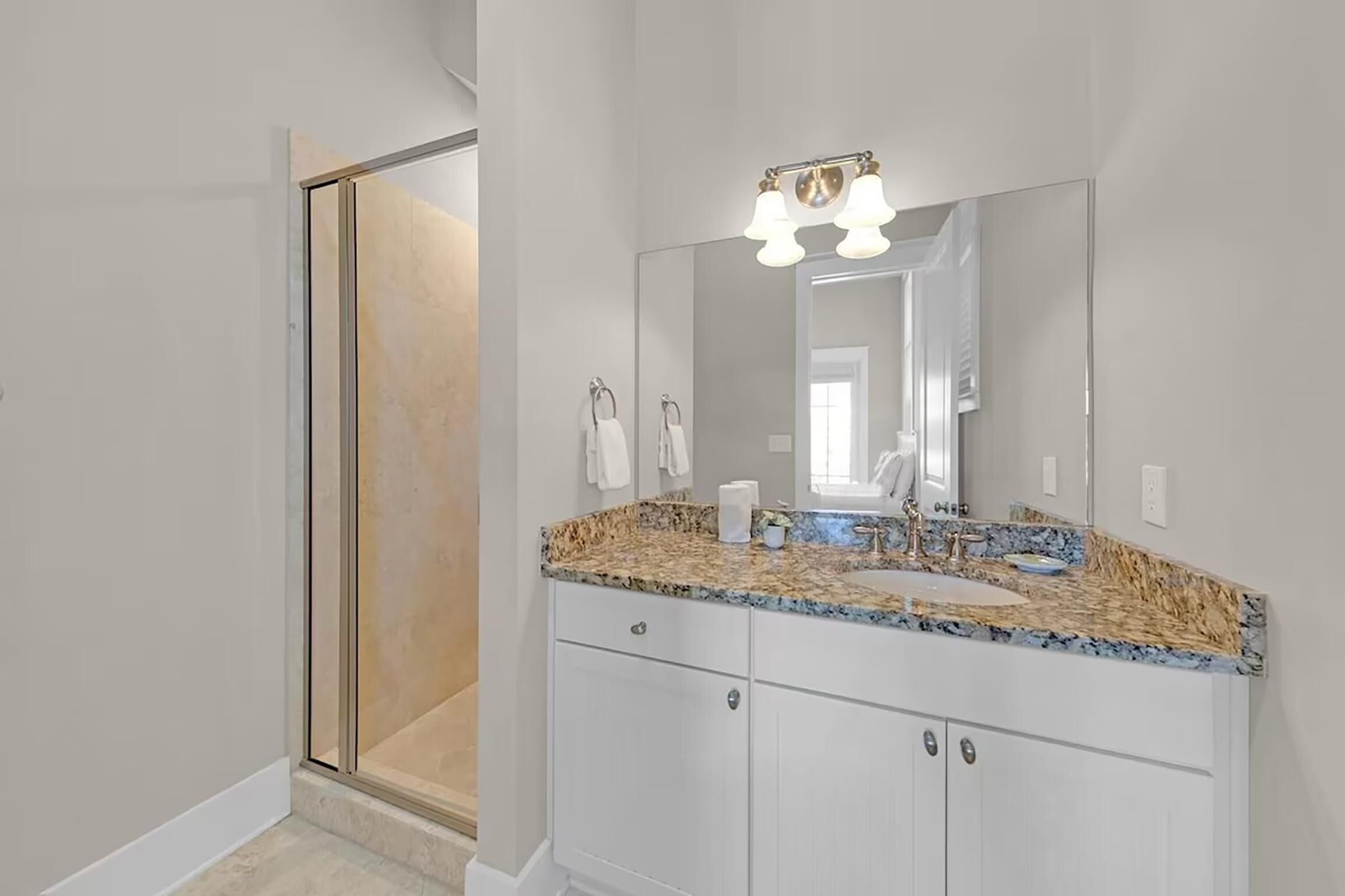A bathroom with a large mirror, a sink, and a shower area.