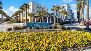 Un hotel con un letrero que dice "GULF PLACE", rodeado de palmeras y flores amarillas.