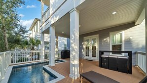 Et overdækket udendørsområde med swimmingpool, træterrasse og udendørs møbler.