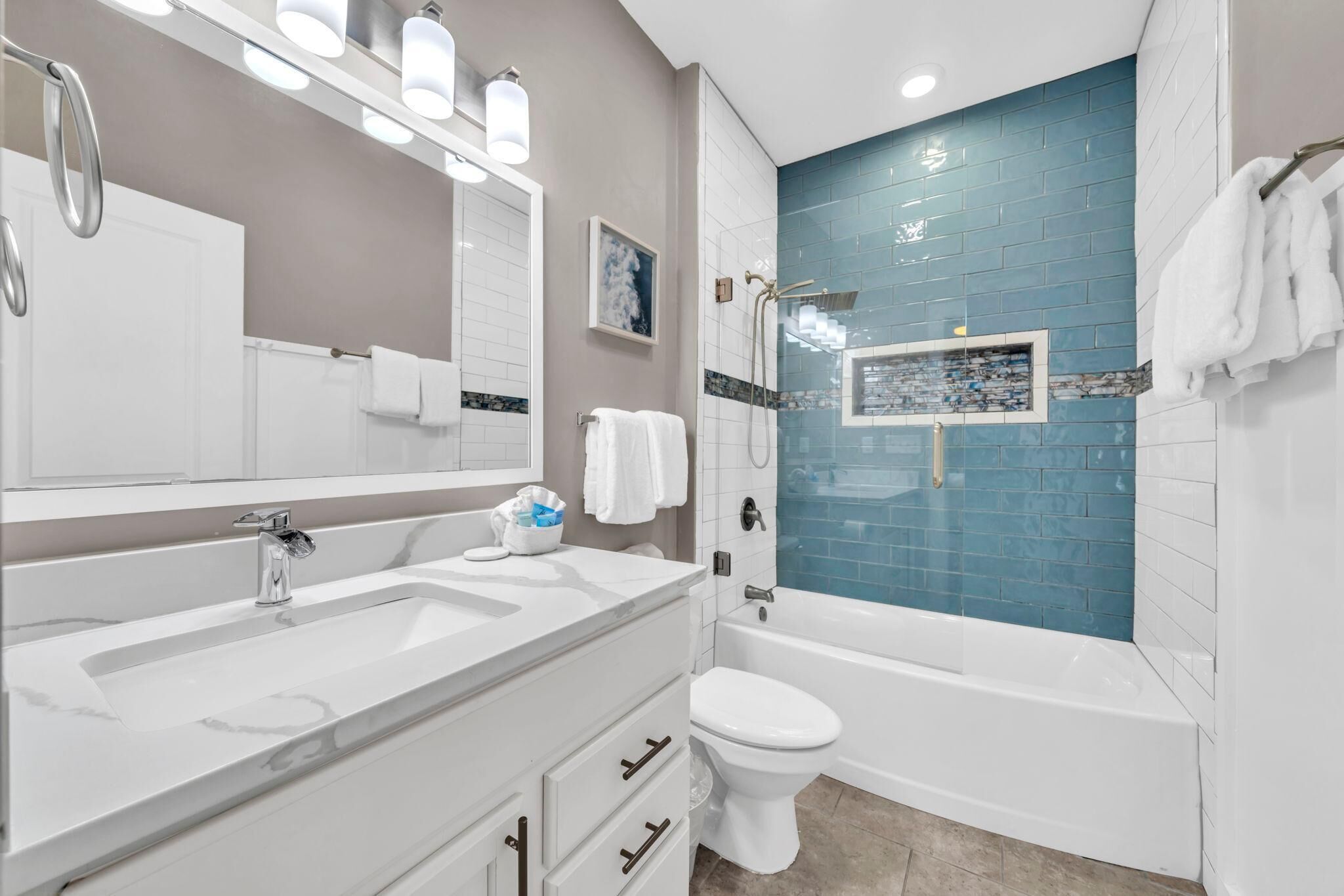 A modern bathroom with a white vanity, a large mirror, a bathtub, and a shower area.