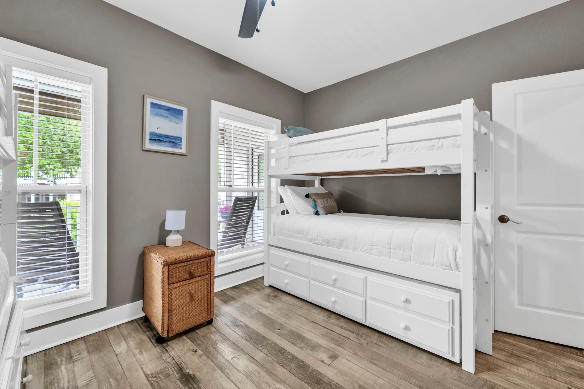 A bedroom with a bunk bed, a small wicker side table, and a door.