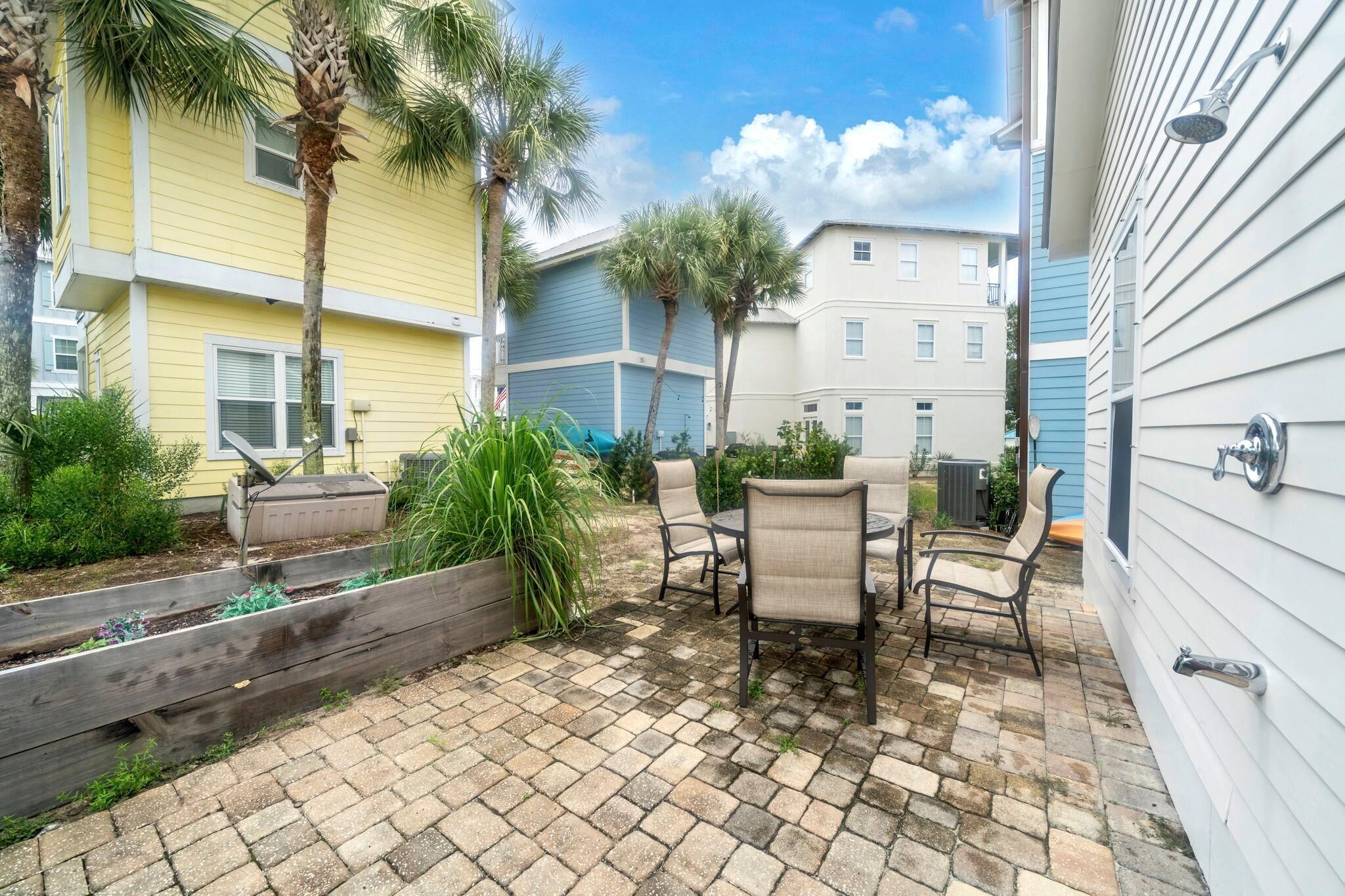 A patio with a brick floor, outdoor furniture, and a view of neighboring buildings.