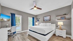 A bedroom with a bed, desk, chair, bedside tables, and a ceiling fan. - Kitties Koop (Santa Rosa Beach)