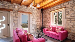 A cozy room with a stone wall, a fireplace, and a pink sofa.