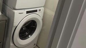 Eine übereinander gestellte Waschmaschine und ein Trockner in einem Waschraum.