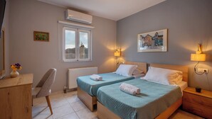 A bedroom with two beds, a wooden dresser, a chair, a window, and a painting on the wall. - Aggeliki House Jetted Tub, Vasiliki & Aggeliki (Rethymno)
