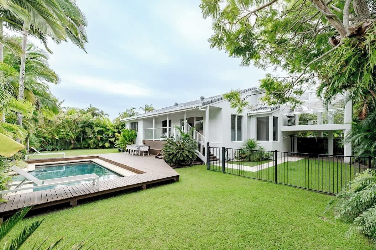 A modern house with a swimming pool, a covered patio, and a fenced backyard.