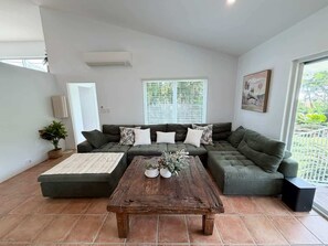 A living room with a sectional sofa, a coffee table, and a potted plant.
