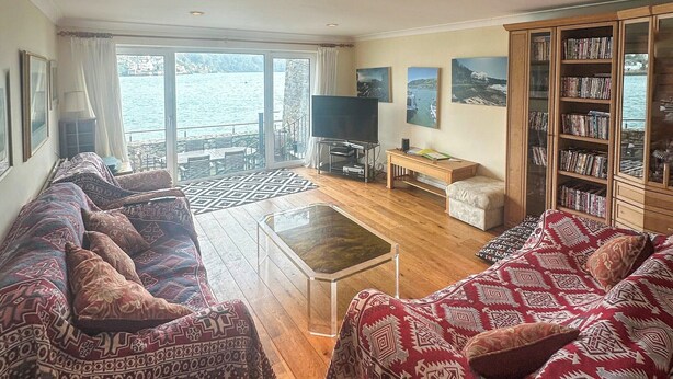 Una sala de estar con sofás estampados, una mesa de centro, un televisor y una estantería.