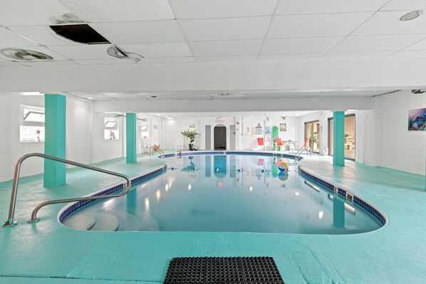 An indoor swimming pool with a clear water surface, surrounded by teal-colored walls and columns. - Charming 2bedroom ocean view beach front condo in Seaside Hts w pool, AC, WiFi (Seaside Heights)