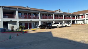 A multi-story motel with a parking lot. - Scottish inns & suites (Houston)