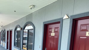 A row of red doors with numbers, each with a window above. - Scottish inns & suites (Houston)