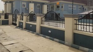Un edificio residencial con techo oscuro, paredes exteriores azul claro y una entrada protegida por una reja.