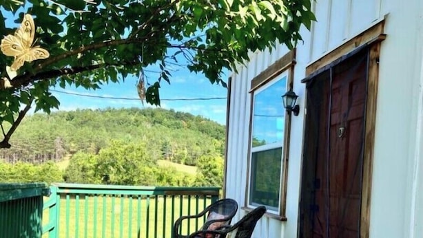 En veranda med gelænder i grøn farve, en trædør og et vindue.