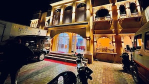 A traditional building with a red carpet entrance, a sign for 'Motion Grip Works', and a parked motorcycle. - siyavar palace (Orchha)