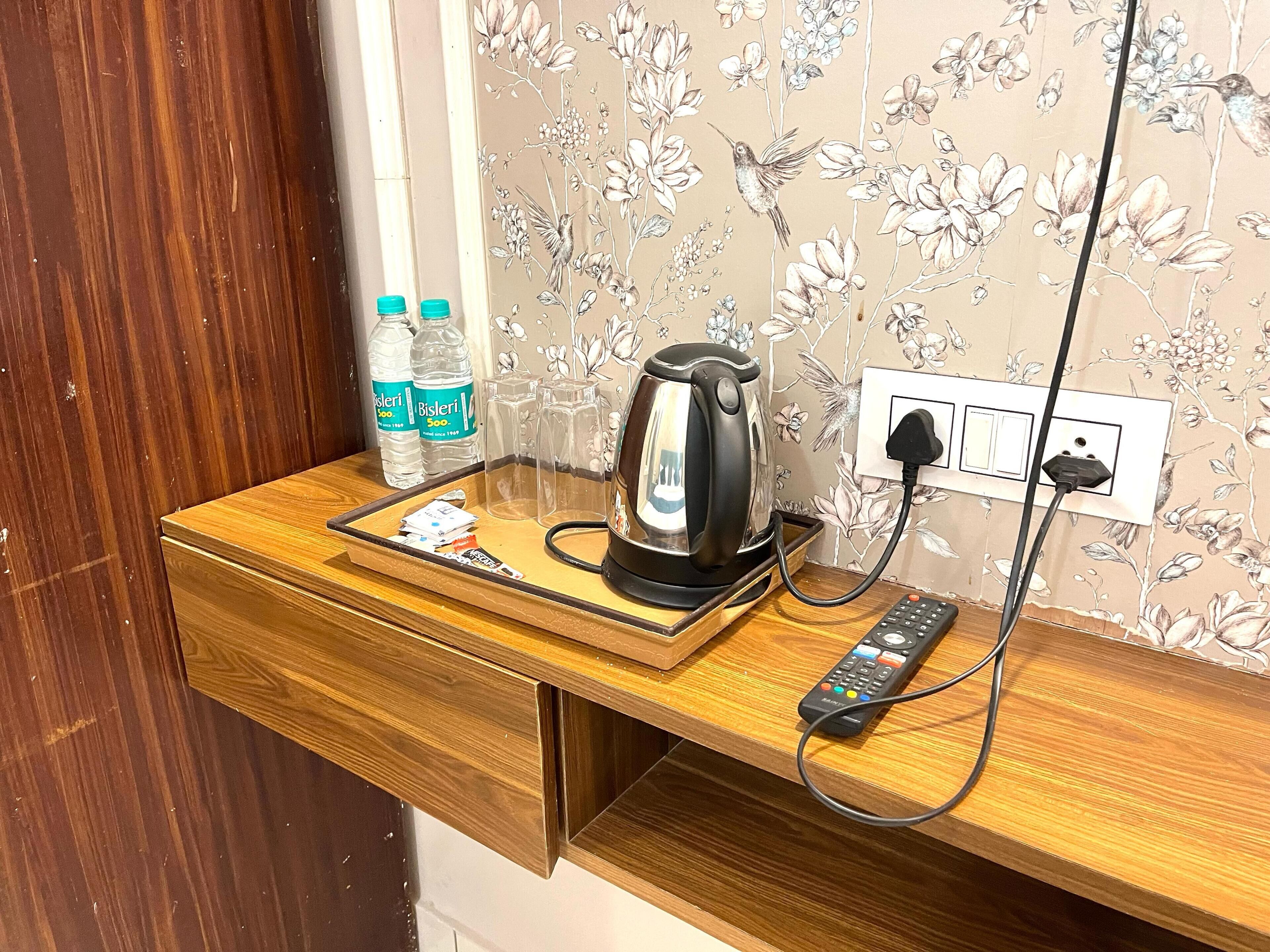 A wooden counter with a kettle, a remote control, and two water bottles.