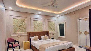 A modern bedroom with a bed, a chair, and a ceiling fan. - siyavar palace (Orchha)