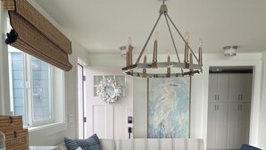 A modern kitchen with a round dining table, dark blue chairs, a hanging light fixture, and a large abstract painting on the wall. - Luxury 4BR Beachfront Retreat. Designer Kitchen, Views, Game Room, Piano, A/C (Tulalip Bay)