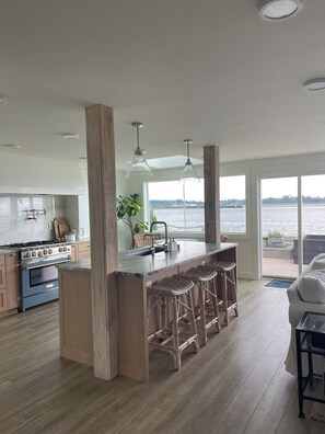 A modern kitchen with a central island, bar stools, and a view of a body of water.