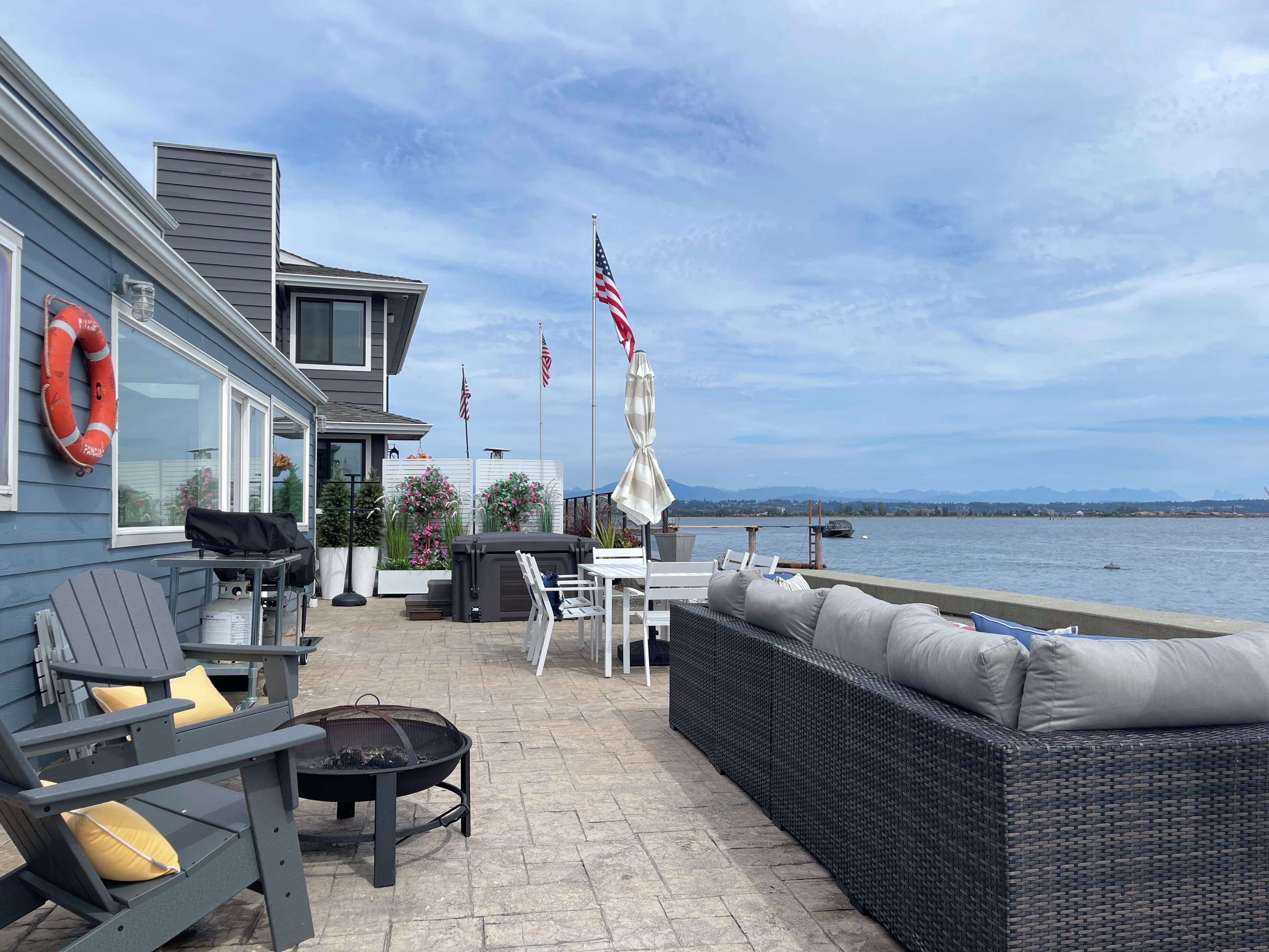 A patio with outdoor furniture, a fire pit, and a view of the water.