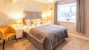 A bedroom with a bed, bedside lamps, a nightstand, a chair, and a window with curtains. - No 31 Killarney Holiday Village for 8! Ideal Location! (Killarney)