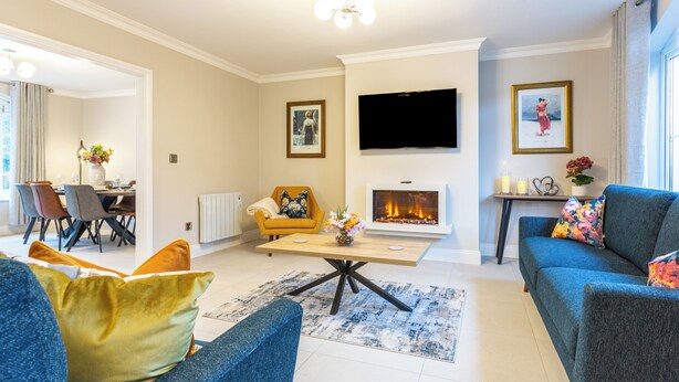 A modern living room with a fireplace, a television, and comfortable seating. - No 31 Killarney Holiday Village for 8! Ideal Location! (Killarney)