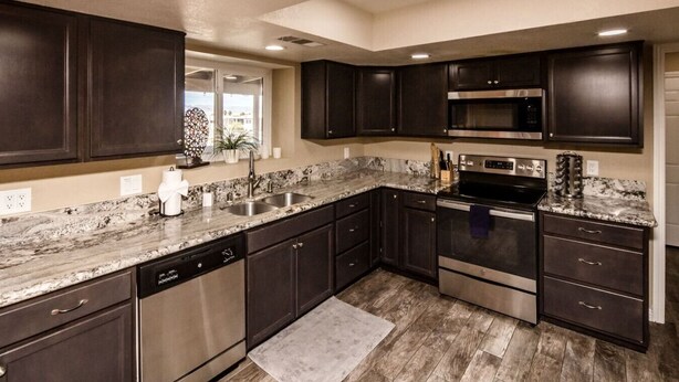 A modern kitchen with dark cabinetry, stainless steel appliances, and a granite countertop. - Havasu Terrace - Pool, Fire Pit, Game Room (Lake Havasu City)