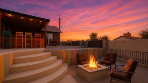 A patio with a fire pit and outdoor seating, surrounded by a house with a covered porch and steps leading up to it. - Havasu Terrace - Pool, Fire Pit, Game Room (Lake Havasu City)