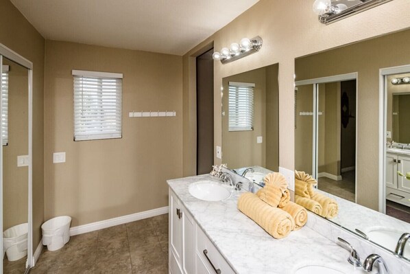 A bathroom with two sinks, a large mirror, and a towel rack with towels.