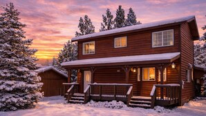 A log cabin with a porch and a covered entryway, surrounded by snow-covered trees and a sunset sky. - Lincoln Log Cabin | Renovated | Near Attractions (Big Bear)