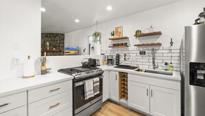 A modern kitchen with white cabinetry, a stainless steel refrigerator, and a built-in oven. - Lincoln Log Cabin | Renovated | Near Attractions (Big Bear)