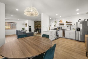 Eine moderne Küche mit weißen Schränken, einem Edelstahlkühlschrank und einem Essbereich mit Holztisch und Stühlen.