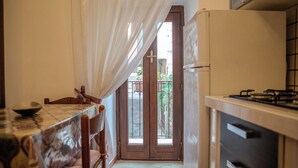 Una cocina compacta con una mesa de comedor, sillas, un refrigerador y una estufa a gas.