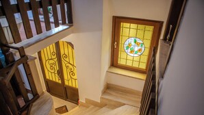 Una escalera con barandas de madera y una puerta de vidrio emplomado con un diseño circular.