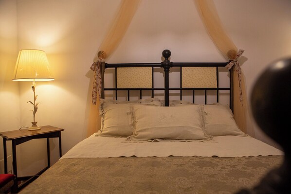 A bed with a canopy, a bedside table with a lamp, and a floral curtain. - La Casa del Fico (Sezze)