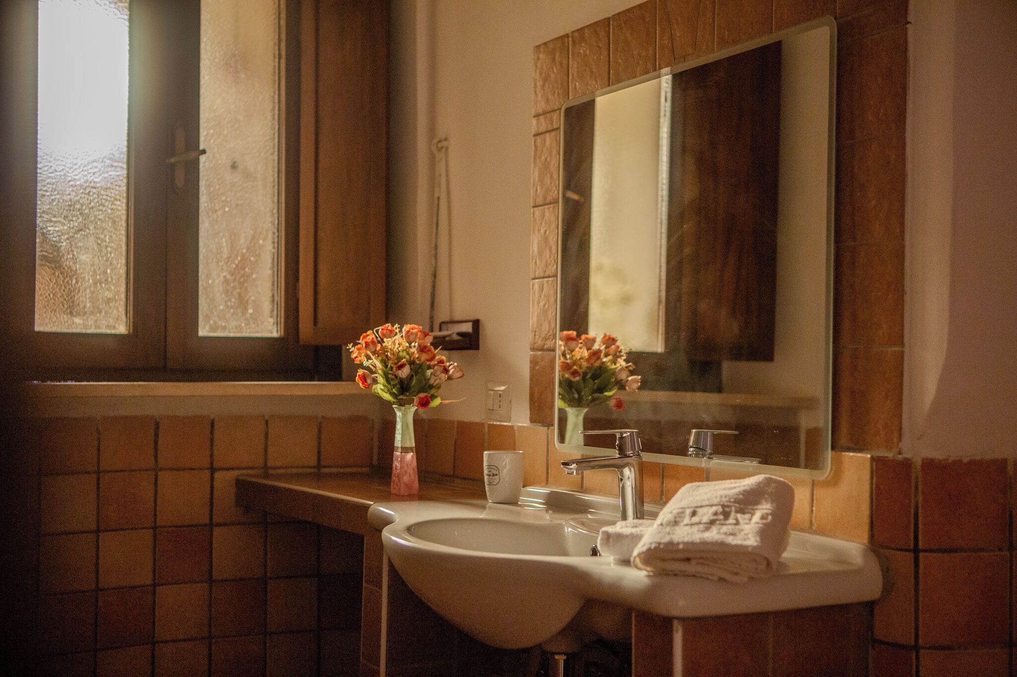 Un baño con lavamanos, espejo y ventana.