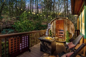 A wooden deck with a fire pit and lounge chairs, surrounded by a forested area. - Romantic Mountain Retreat I Hot Tub I Sauna I Fire pit I Art Studio (Blue Ridge)