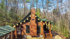 A cabin with a chimney, a porch, and a deck.