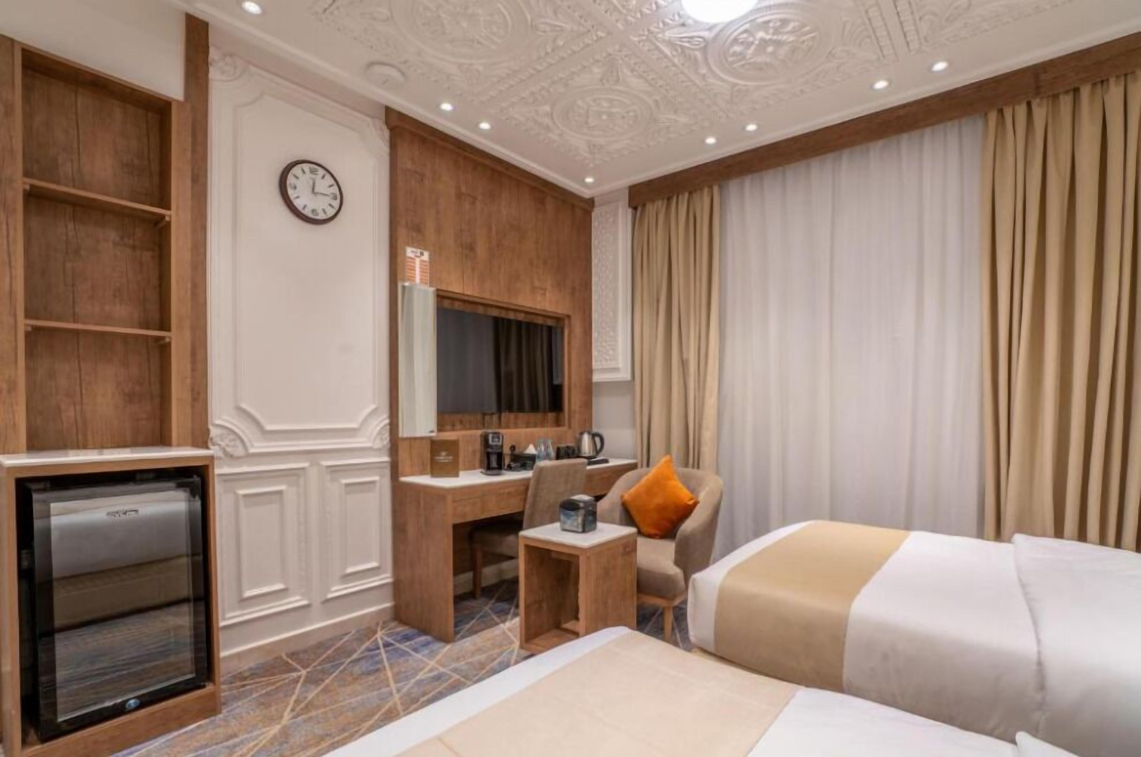 Une chambre d’hôtel comprenant un lit, un bureau avec une chaise, une télévision, une horloge et un mini-bar.