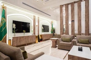 A modern lobby with a wooden reception desk, sofas, a flat-screen TV, and decorative plants. - Nars Plus Al Naeem Hotel (Jeddah)