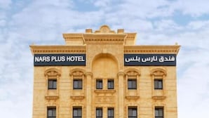 Un hôtel à plusieurs étages, doté d’une architecture classique, avec une entrée imposante, un espace d’accueil et un panneau indiquant l’emplacement du parking.