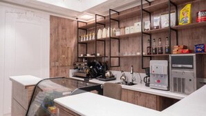 Une cuisine moderne équipée d’une machine à café, d’étagères remplies d’ustensiles de cuisine et d’un distributeur d’eau.