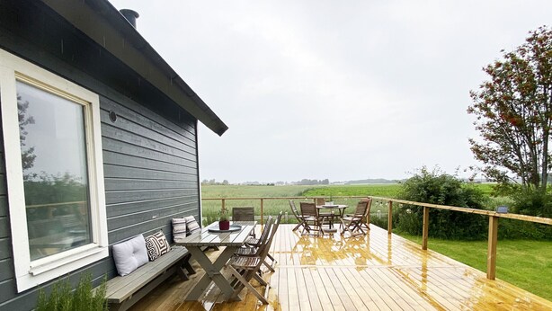 Een terras met een tafel, stoelen, een bloempot en uitzicht op het landschap.